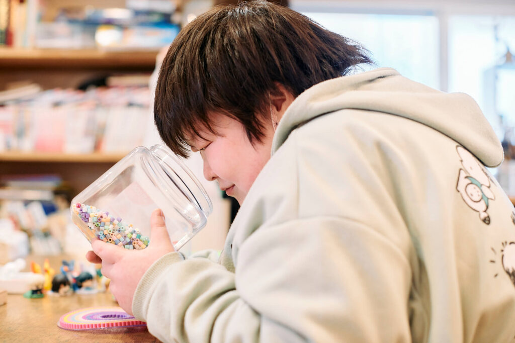 アイロンビーズの入った瓶を覗く仁井田晶子さん